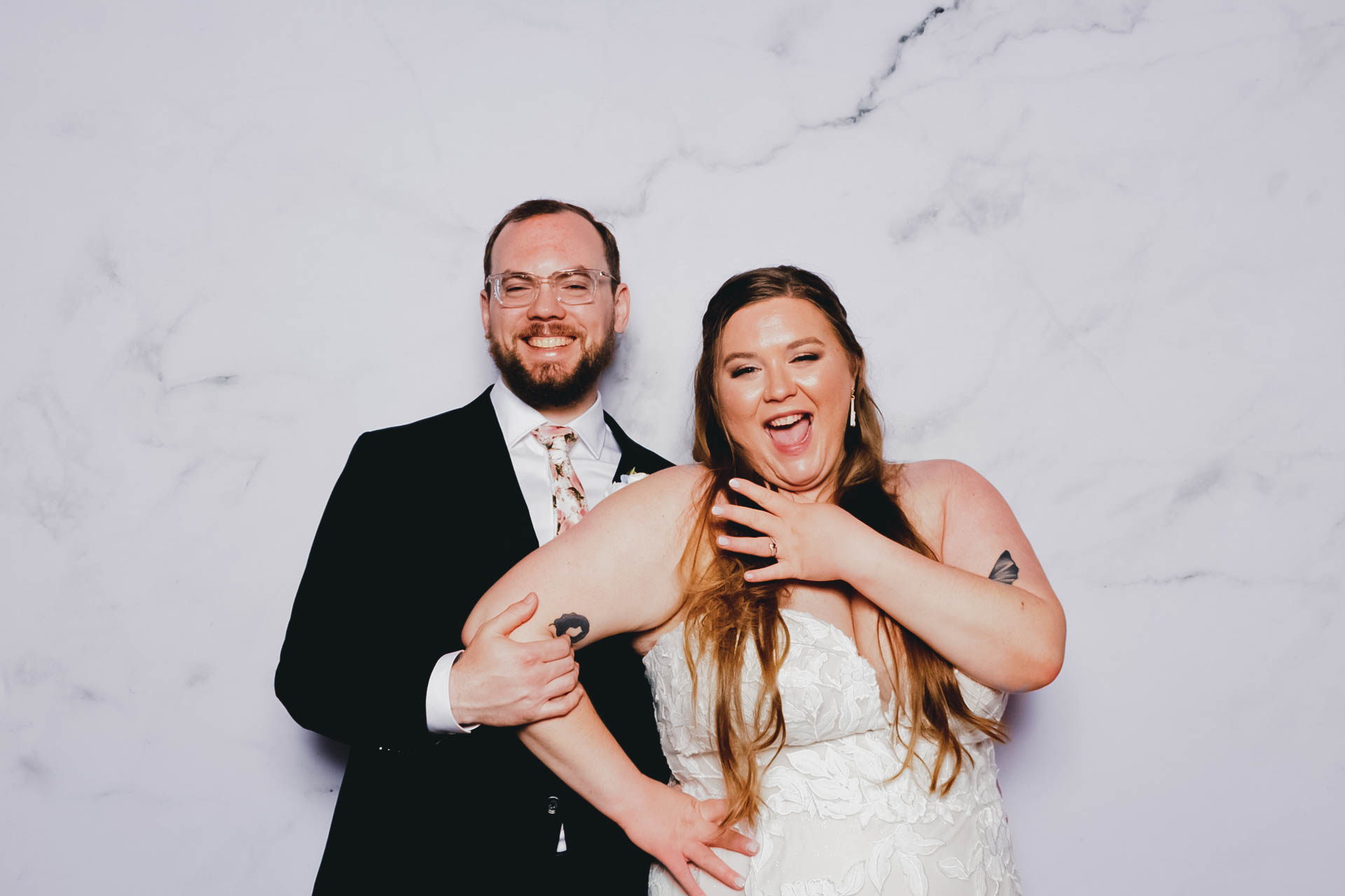 Bride and groom smiling at the camera on a marble background